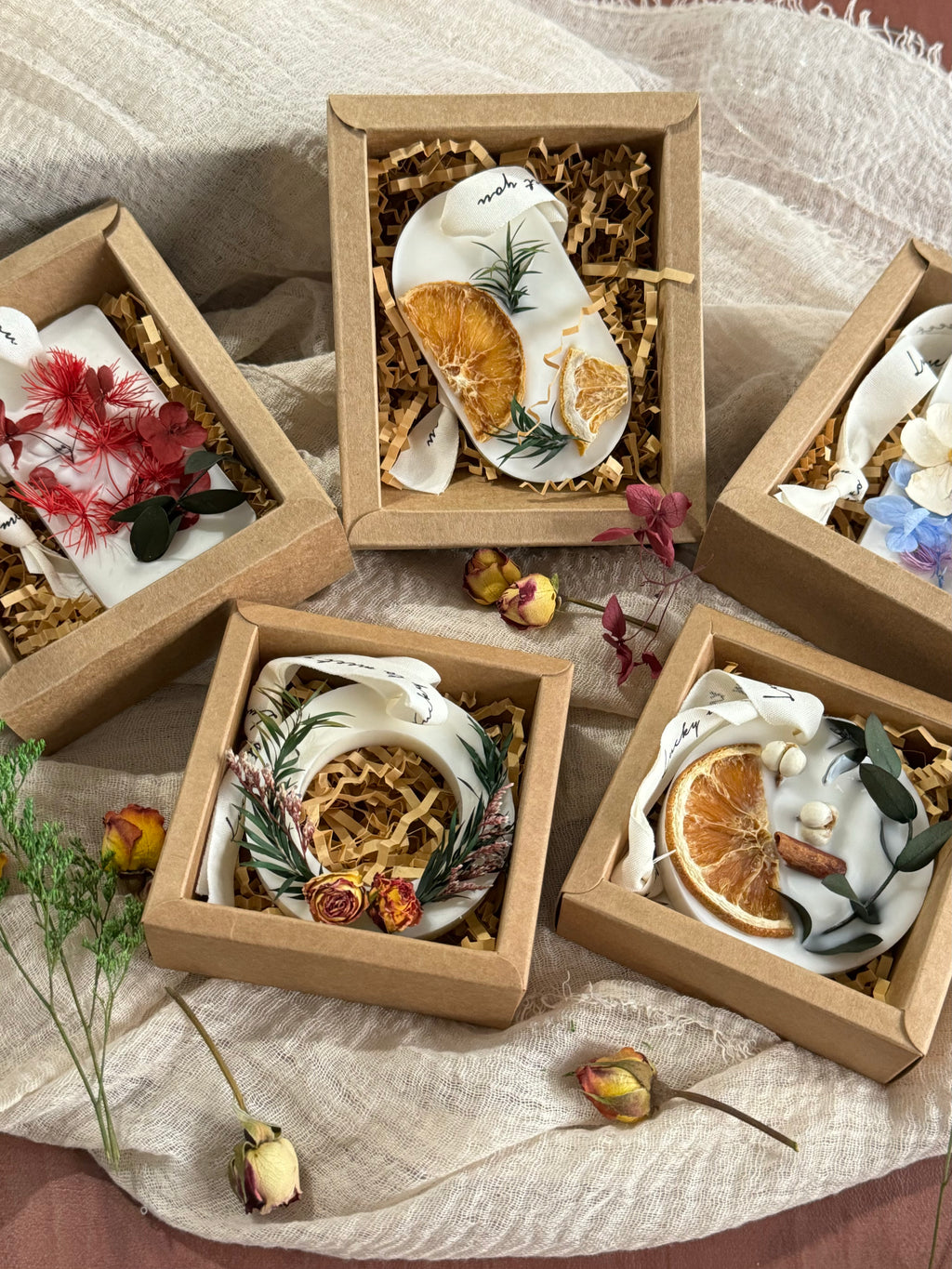 A collection of handmade scented wax tablets with dried flowers and citrus slices in kraft paper gift boxes. Luxury soy wax sachets as a free premium gift with purchase for home fragrance decoration.
