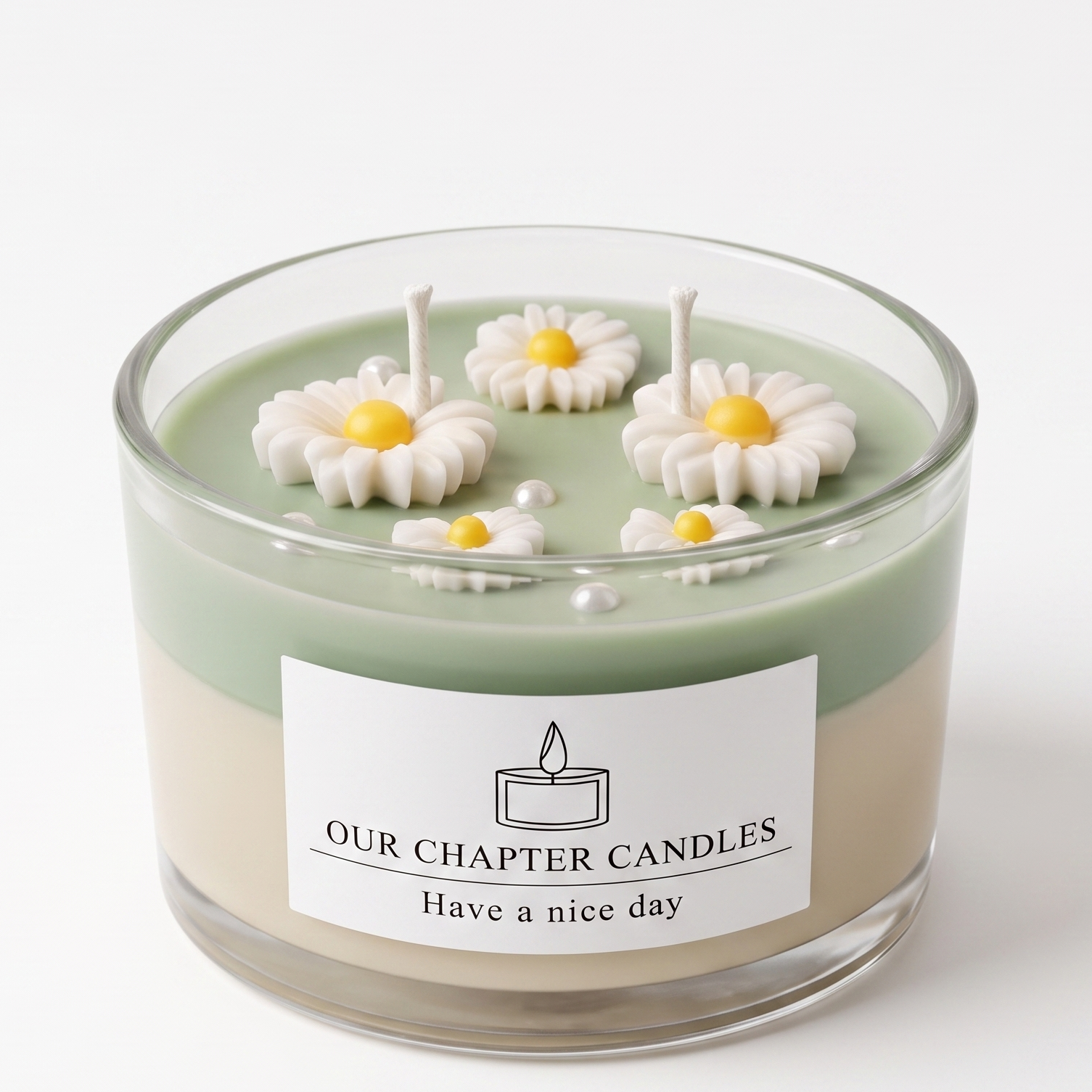 A luxury dual-layer daisy botanical soy wax candle in a clear glass jar based on image_3986bd.jpg. Features a solid light-beige base, a soft sage green top layer decorated with realistic white wax daisies and mini pearls on a white background.