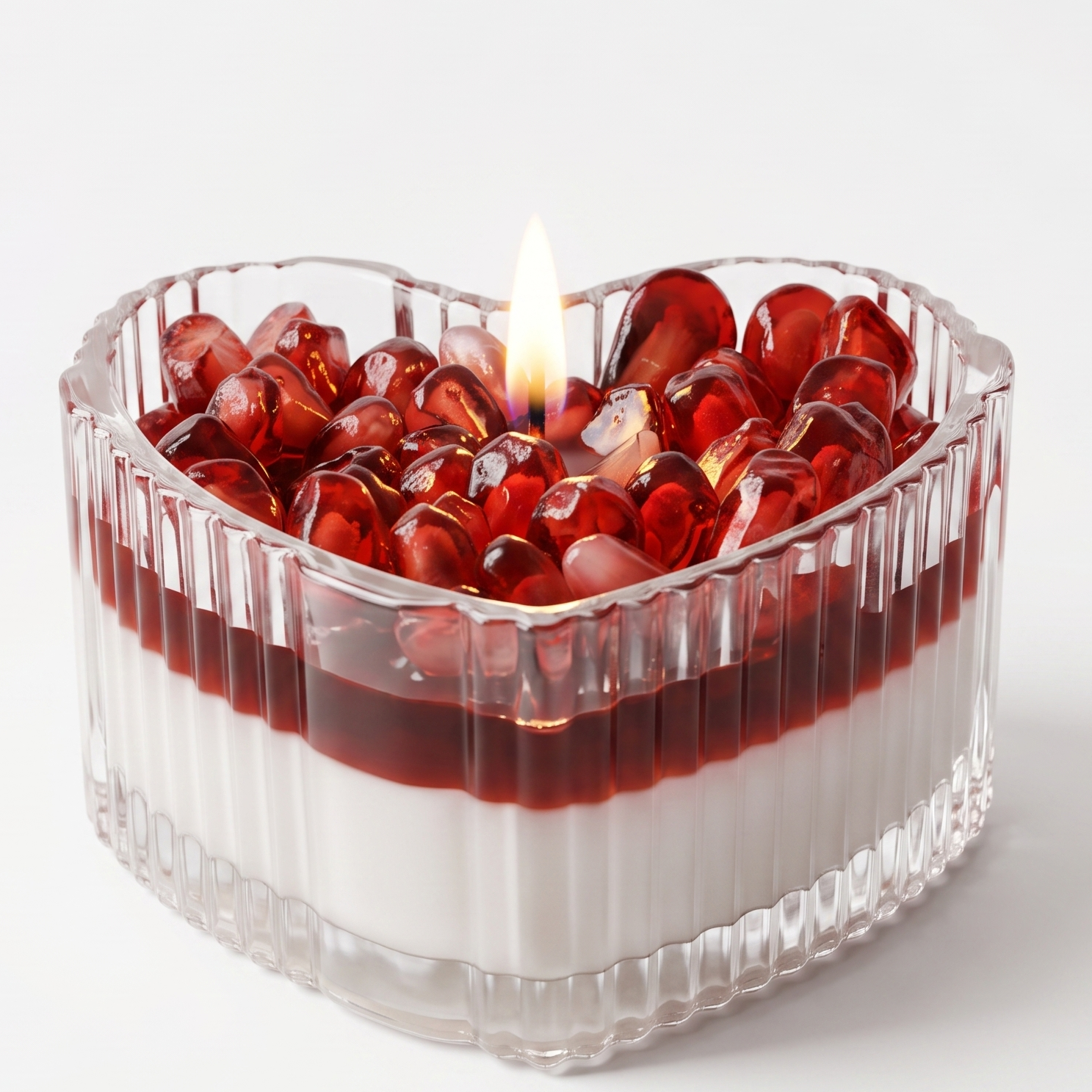 Extreme macro close-up of a lit valentine candle showcasing the glossy waxy texture of ruby pomegranate seeds and a glowing flame. High-resolution view of the ribbed heart-shaped glass with distinct soy and gel wax layers.