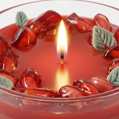 Extreme macro close-up of a lit botanical candle showcasing the glossy waxy texture of ruby pomegranate seeds and carved green mint leaves. High-resolution view of the glowing flame and clean rectangular "OUR CHAPTER CANDLES" label.