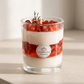 Serene aesthetic lifestyle setting featuring an unlit multi-layer pomegranate dessert jar candle on a minimalist travertine table. Clean and bright modern room atmosphere, perfect for premium luxury boutique aromatherapy gifting.