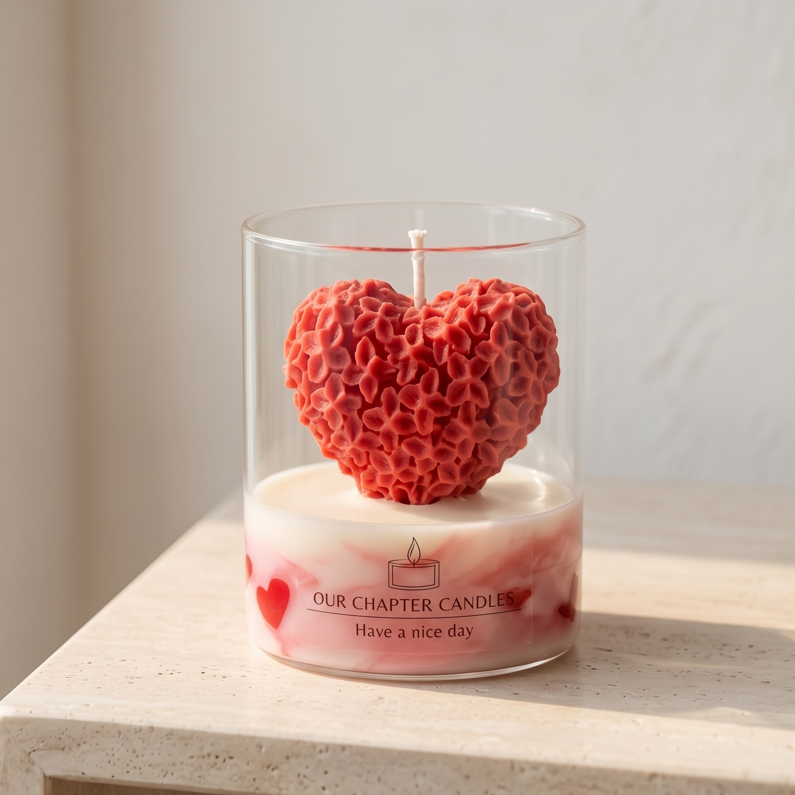Serene aesthetic lifestyle setting featuring an unlit red carved floral heart jar candle on a minimalist travertine table. Clean and bright modern room atmosphere, perfect for premium luxury boutique anniversary or wedding gifting.