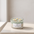 Serene aesthetic lifestyle setting featuring an unlit dual-layer daisy flower jar candle on a minimalist travertine surface. Clean and bright modern room atmosphere, perfect for premium aromatherapy gifting.